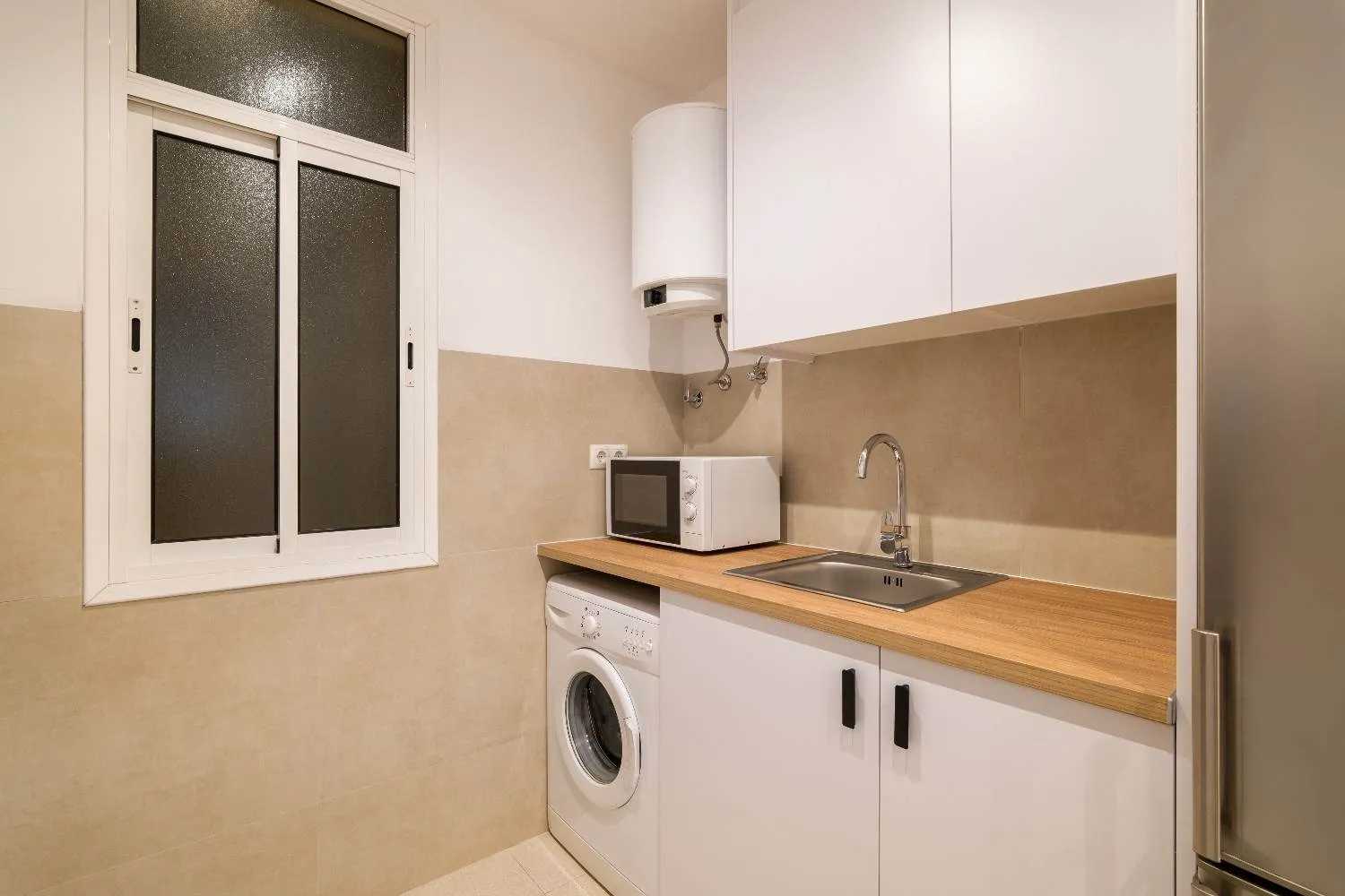 Small home kitchen with a washer, microwave and wall-mounted water heater